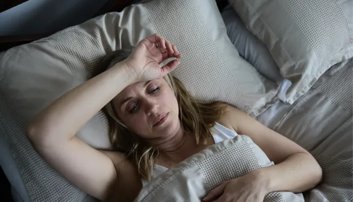 Schlaflose Frau, die sich im Bett frustriert fühlt.